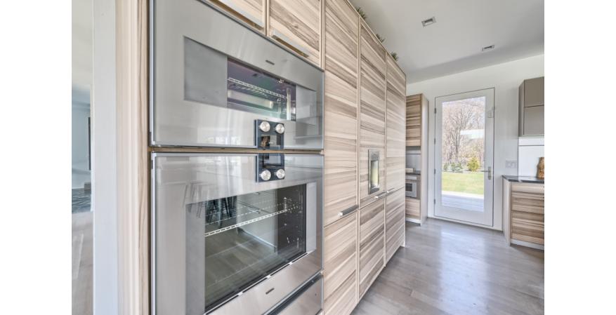The kitchen in No. 16 Fieldview Lane features cabinets made with core ash wood, which boasts a livelier grain and contrasts with the subtler grain and darker hues in the kitchen next door.