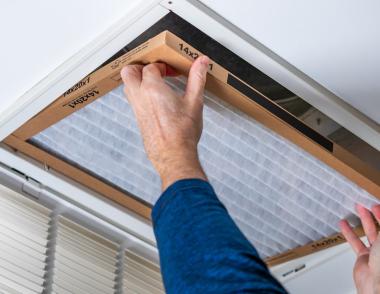 Person installing new air filter in vent